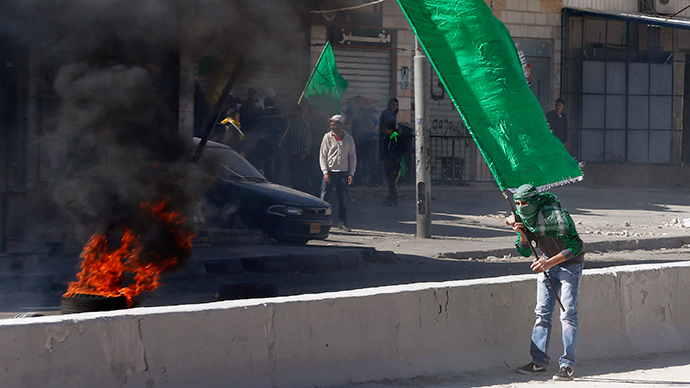 A Palestinian protester holds a Hamas flag during clashes with Israeli troops following a protest against what organizers say are recent visits by Jewish activists to al-Aqsa mosque
